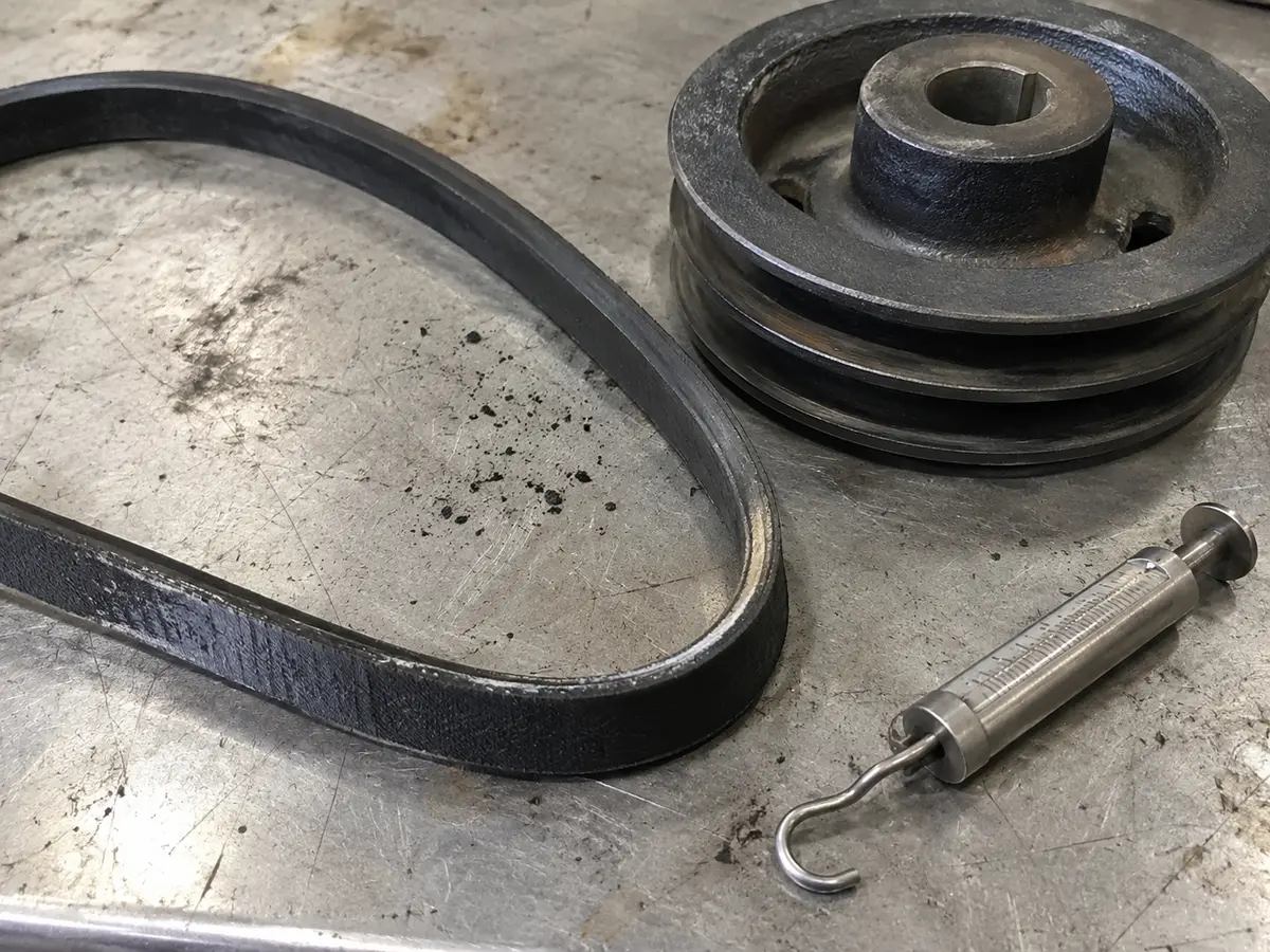 Glazed V-belt and pulley being inspected after repeated slippage